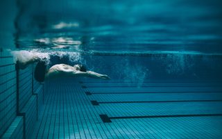 Underwater shot of male swimmer turning over in swimming pool. Pro male swimmer in action inside pool.